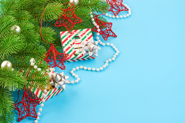 Christmas background with fir branches, various christmas decorations, colored garlands and beads, on a blue background. Christmas decoration. Christmas background. Space for text.