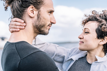 Young couple embracing with hands at the nape of the neck with the sea out of focus in the background