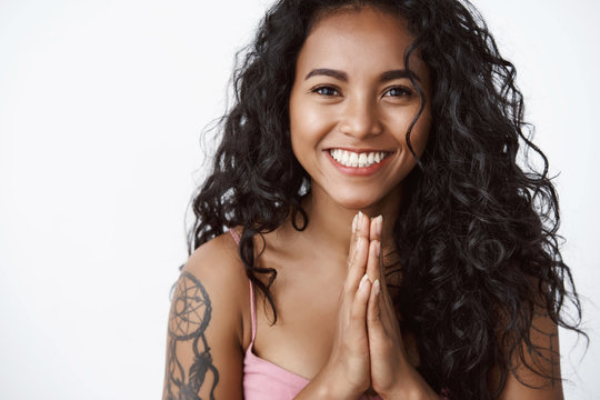 Close-up attractive grateful charming african-american curly-haired girl with tattoos, hold hands in pray smiling toothy, look grateful appreciate friends help, standing white background