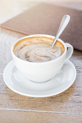 White big cup of delicious coffee on wooden table in sunlight.