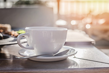 White big cup of delicious coffee on wooden table in sunset light with copy space.