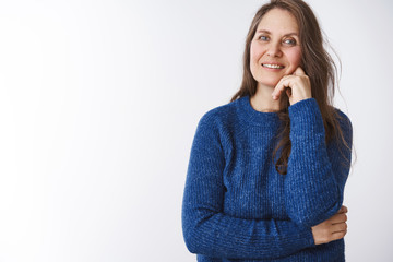 Waist-up shot of charming middle-aged granny leaning cross hand over body touching face gently as smiling and looking at camera entertained, feeling loved, proud of strong and united family