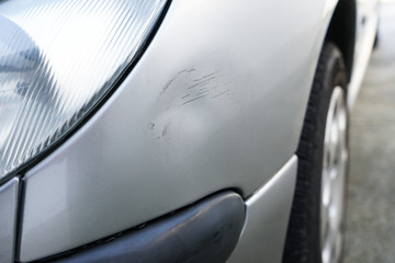 Close up of dent and scratches on side of old silver gray car. Damage from crash accident, parking lot or traffic. - obrazy, fototapety, plakaty