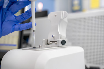 The researcher drops 2 micro-liters of the sample on pedestal to measures the RNA concentration and quality using the Nano Drop spectrophotometer in the laboratory room.