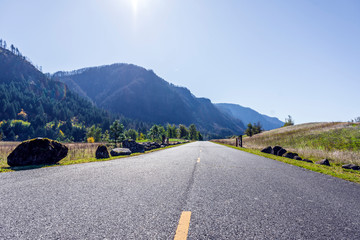 Marked road in Columbia Gorge with mountains and trees and boulders along the curb