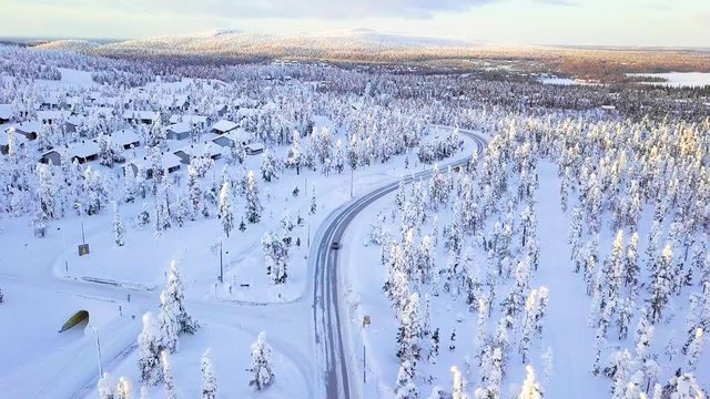 Aerial view of snow mountain landscape with curvy windy road and snow covered forest in Finland Lapland, from drone in 4k