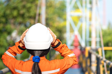 Female worker is wearing safety hardhat helmet to prepare for start the job, with background of...