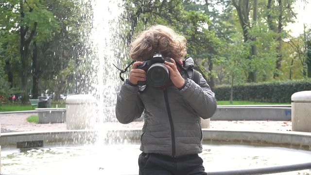 Bambino impara a fotografare con una macchina fotografica reflex professionale in un parco 