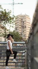 young woman in with hat stacked on a railing,background of buildings,lifestyle