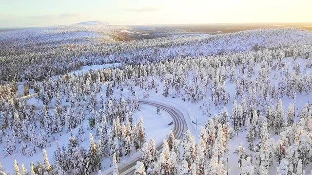 Aerial view of snow mountain landscape with curvy windy road and snow covered forest in Finland Lapland, from drone in 4k
