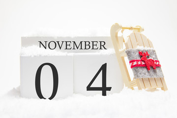 Autumn calendar made of wooden cubes with the date of November 4, the concept of the first snow and future holidays. Close-up.