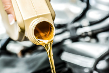 Pour yellow motor oil into car engine. Maintenance service change liquids and fluid.