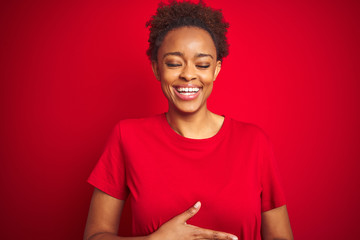 Young beautiful african american woman with afro hair over isolated red background smiling and laughing hard out loud because funny crazy joke with hands on body.