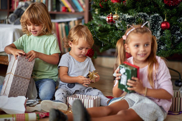 Fototapeta na wymiar Happy childhood on Christmas.Kids opening Xmas presents.