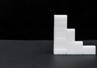 white sugar cubes stacked in a pyramid, sugar level, on a dark background