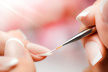 Woman nails manicure close up. Nail profi paint white color or french with thin brush and pink...