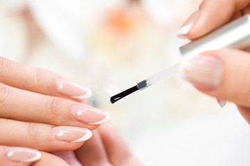 Beautician in luxury salon applying lacquer or varnish gel on nails..Manicure nail paint with brush or artist polish modelation technique.