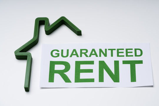 Green House Model And Paper With Guaranteed Rent Text