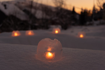 Ice lanterns with tea lights in the snow glowing at night. Focus on one lamp in the foreground....