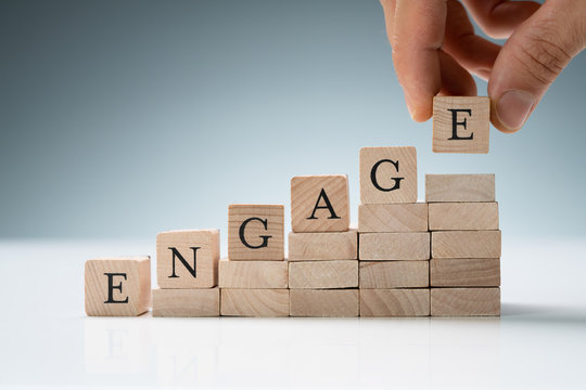 Person Arranging Wooden Blocks Showing Engage Text