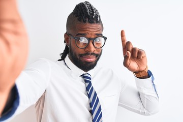 African american businessman make selfie by camera over isolated white background surprised with an idea or question pointing finger with happy face, number one