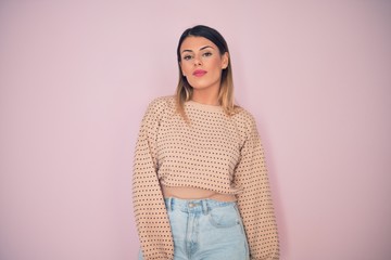 Obraz premium Young beautiful woman wearing fashionable clothes standing over isolated pink background
