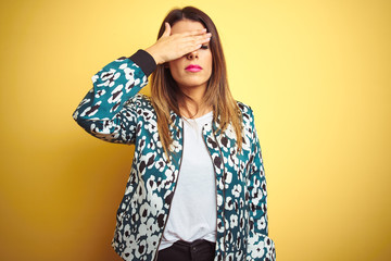 Naklejka premium Young beautiful woman wearing casual jacket over yellow isolated background covering eyes with hand, looking serious and sad. Sightless, hiding and rejection concept