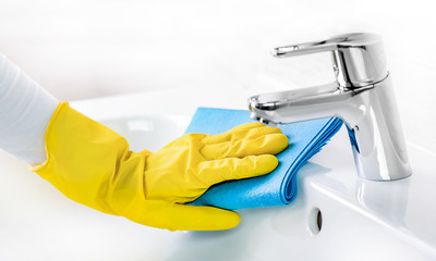 Woman maid or charwoman cleaning modern new basin in bathroom, water tap clean using yellow gloves...