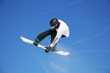 Skier Snowboarder jumping through air with sky in background