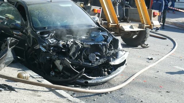 car with smoke from the motor after a big road accident, rumpled car trim and bumper, closeup, accident on the road in the city