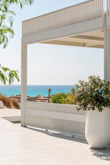 Fototapeta na wymiar Luxurious white terrace in a tropical resort with sea views. Bright blue sky on a sunny day. Background. Space for text. Vertical.