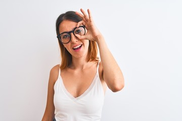 Beautiful redhead woman wearing glasses over isolated background doing ok gesture with hand smiling, eye looking through fingers with happy face.