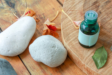 small green glass pot with essential oil on a wooden table with stones and dried flowers
