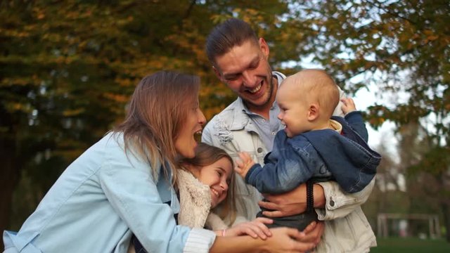 Young couple, toddler and teen girl cuddling in autumn park, happy family vacation. Family with two children in autumn park