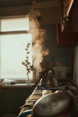  Russian cuisine. A metal kettle boils on the stove. Brown table with dishes that dry, blue tiles, sink