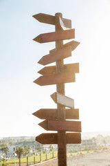 Empty wooden sign with direction signs on a blue sky background. Solar flare. Vertical.
