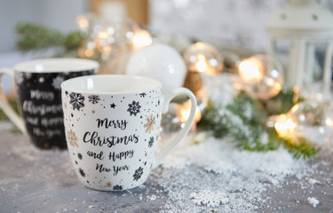 Obraz na płótnie Canvas tea Cup and Christmas decorations on table against blurred lights