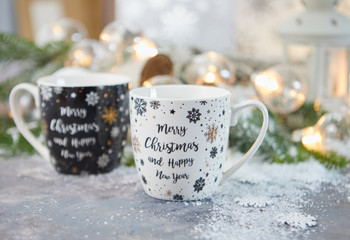 tea Cup and Christmas decorations on table against blurred lights