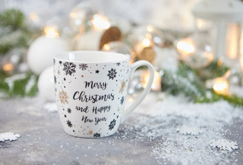 tea Cup and Christmas decorations on table against blurred lights
