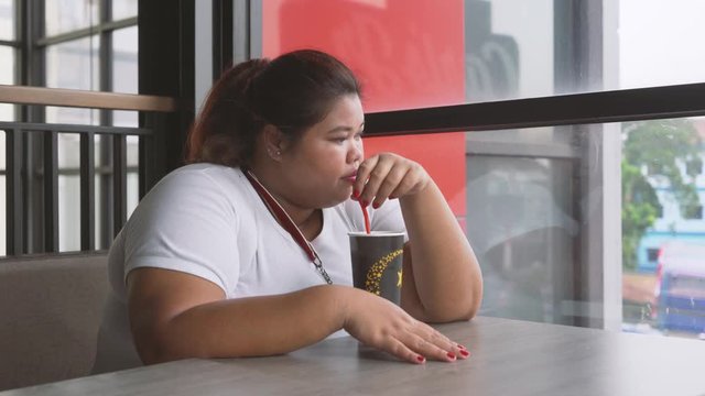 Obese woman drinking soft drink in the cafe