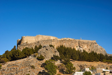 White houses of a greek town and a medieval fortress in Lindos .