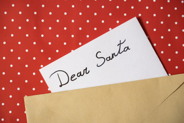 Letter to Santa in an envelope. Red polka dot background. Close-up