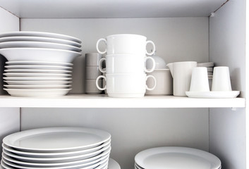 Fototapeta na wymiar White Cupboard with white crockery in the kitchen, various clean dishes