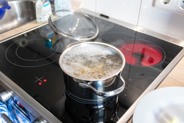 Hausfrau kocht Nudeln und Wasser für das Mittagessen mit der Familie in silbernen Töpfen auf...