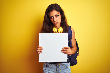 Obraz na płótnie Canvas Young beautiful student woman holding banner standing over isolated yellow background with a confident expression on smart face thinking serious