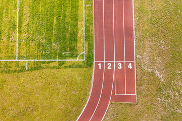 Top view of red running tracks and green grass lawn. Infrastructure for sports activities.