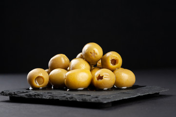 several olives lie on a black board on a black background macro super macro