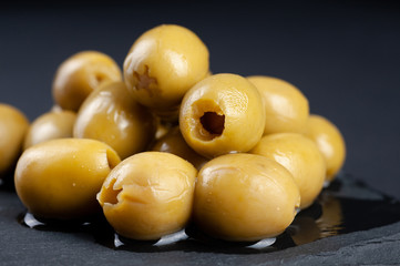 several olives lie on a black board on a black background macro super macro