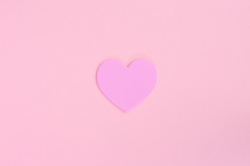 A single love heart in the centre of a pink background with copy space representing Valentines Day and romance