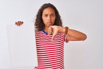 Young brazilian woman holding banner standing over isolated white background with angry face, negative sign showing dislike with thumbs down, rejection concept